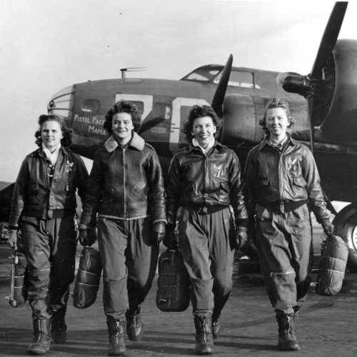Female pilots standing beside a World War II aircraft